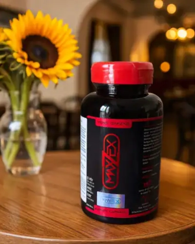 Viên uống Maxzex Nga tăng kích thước dương vật – Chai Maxzex đen trên bàn cạnh bình hoa hướng dương