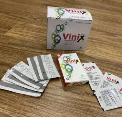 Tem ngậm Vinix 100mg Hàn Quốc chính hãng – thùng hộp Vinix và nhiều gói film xòe ra trên bàn gỗ