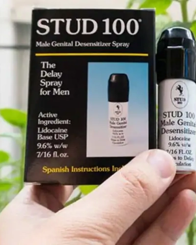 Xịt kéo dài thời gian quan hệ Stud 100 chính hãng – Tay cầm hộp và chai Stud 100 nền cây xanh